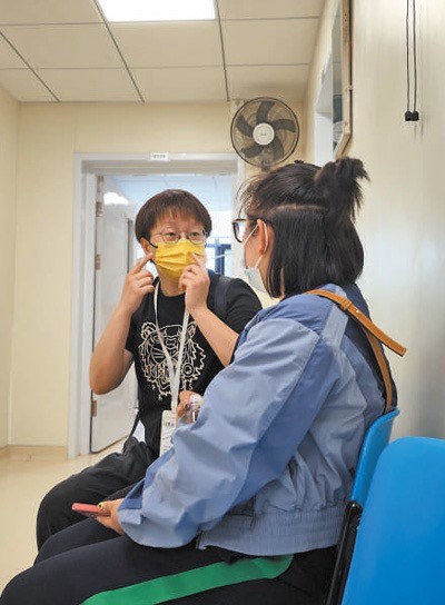 在中国中医科学院广安门医院，陪诊员（左）陪同患者等候就诊。